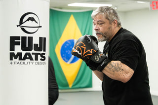Older adult student in boxing gloves working the heavy bag at One Way Martial Arts in Alexandria, VA