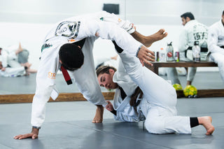 Two BJJ students in white gis drilling a guard pass during class at One Way Martial Arts in Alexandria, VA