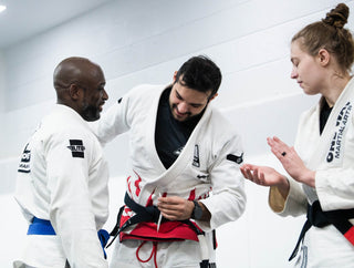 BJJ black belt coach tying his belt while talking with students at One Way Martial Arts in Alexandria, VA