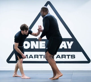 Two students drilling striking defense in front of the One Way Martial Arts logo in Alexandria, VA
