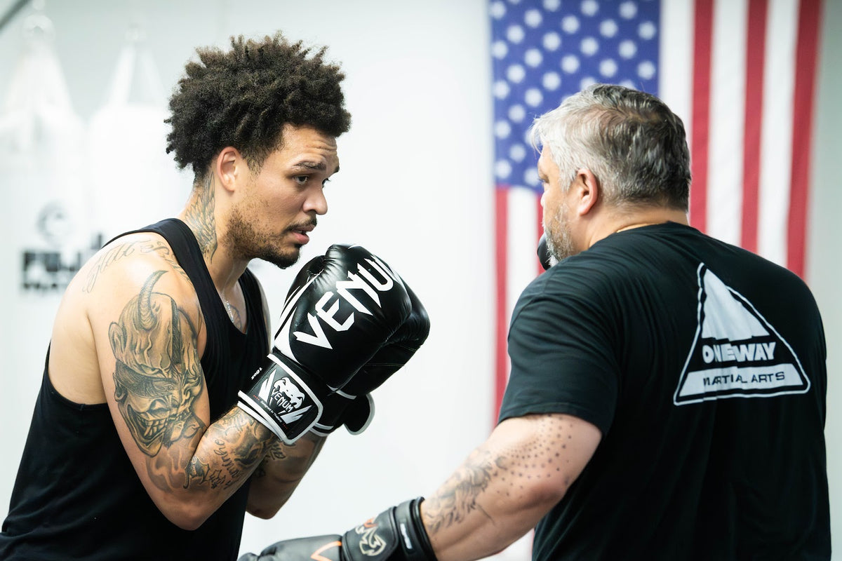 Coach holding focus mitts for a boxing student at One Way Martial Arts in Alexandria, VA