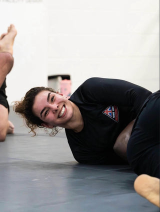 Coach Giovanna Amaral, IBJJF Pan American Champion and BJJ coach at One Way Martial Arts in Alexandria, VA, smiling during No-Gi training