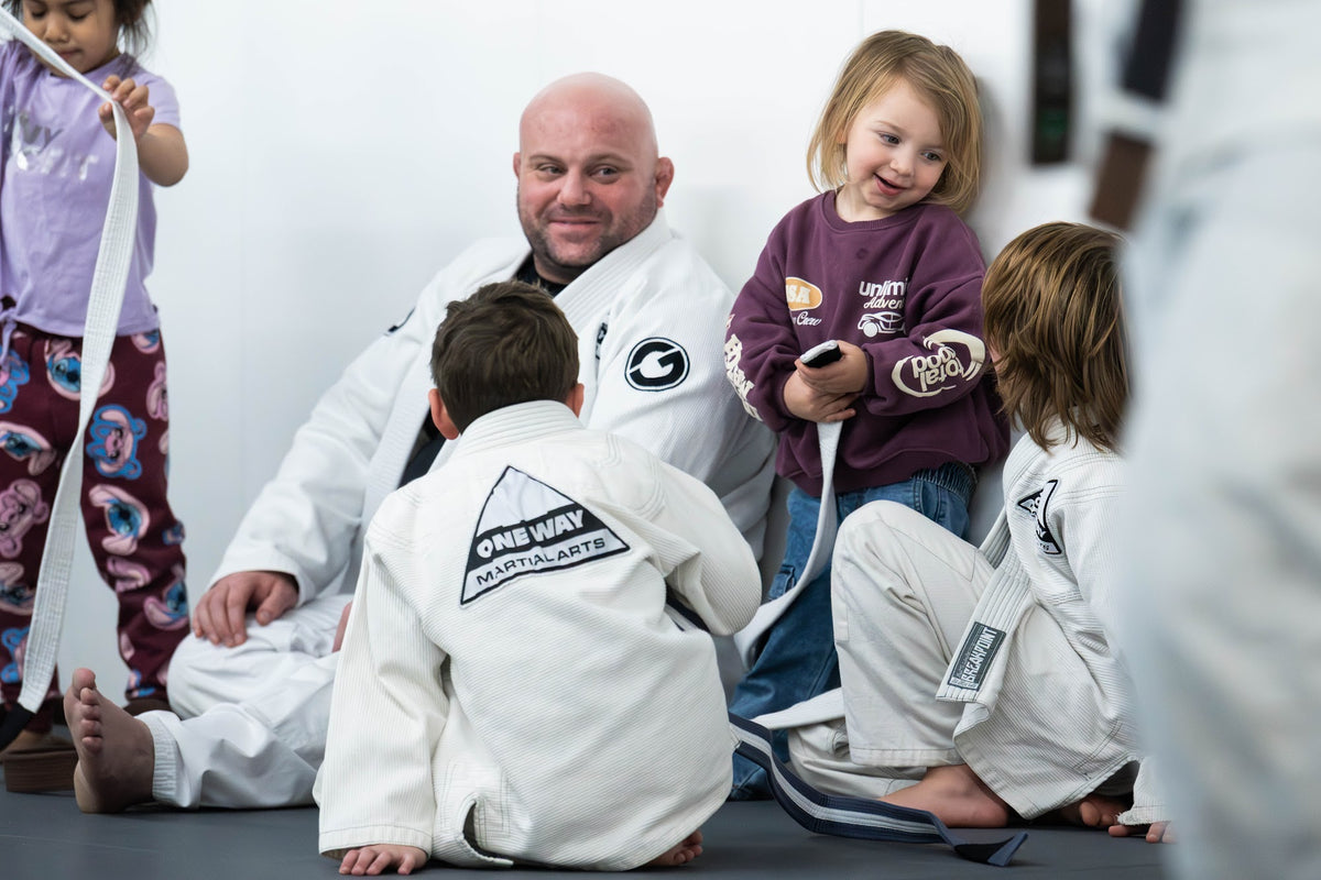 Coach sitting with young students during Kids BJJ class at One Way Martial Arts in Alexandria, VA