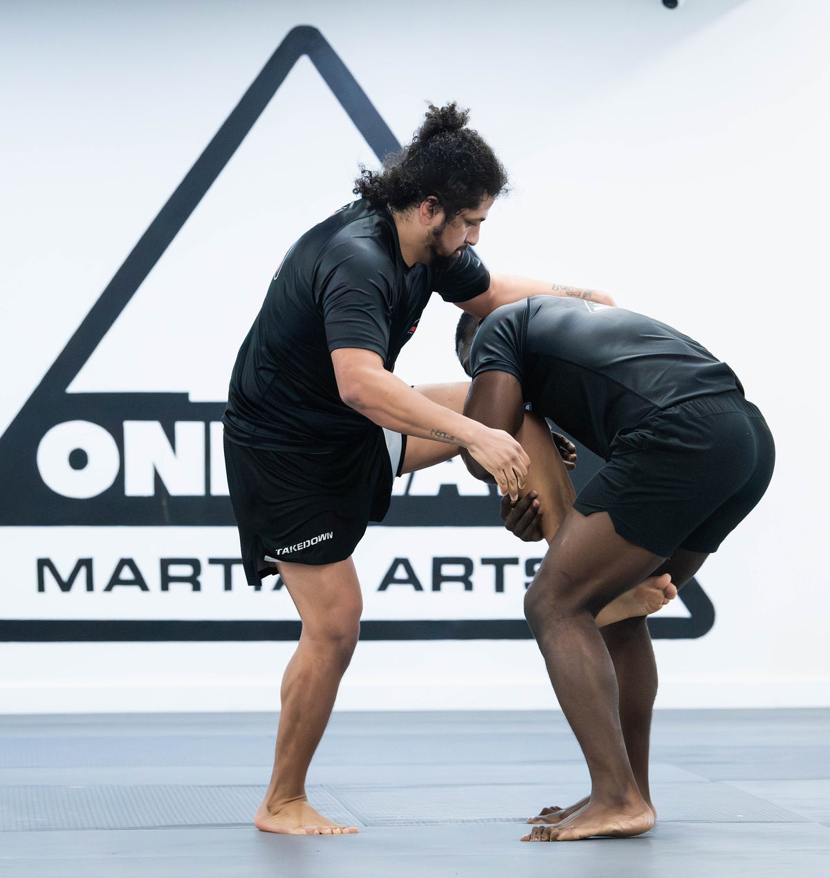 Two grapplers hand fighting in front of the One Way Martial Arts logo in Alexandria, VA