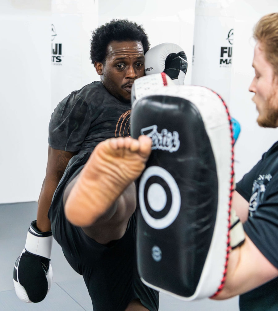 Muay Thai student kicking a pad held by a coach at One Way Martial Arts, Alexandria VA
