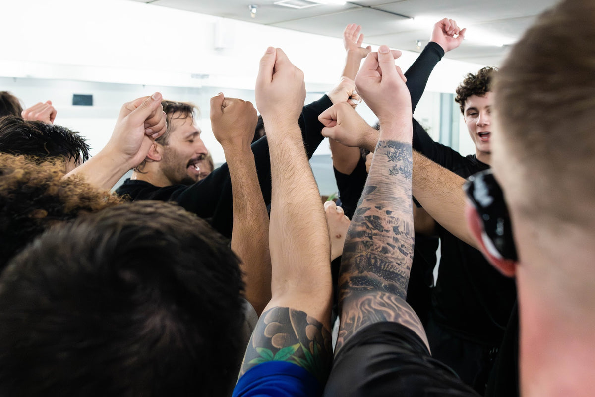Team huddle with hands raised after class at One Way Martial Arts in Alexandria, VA