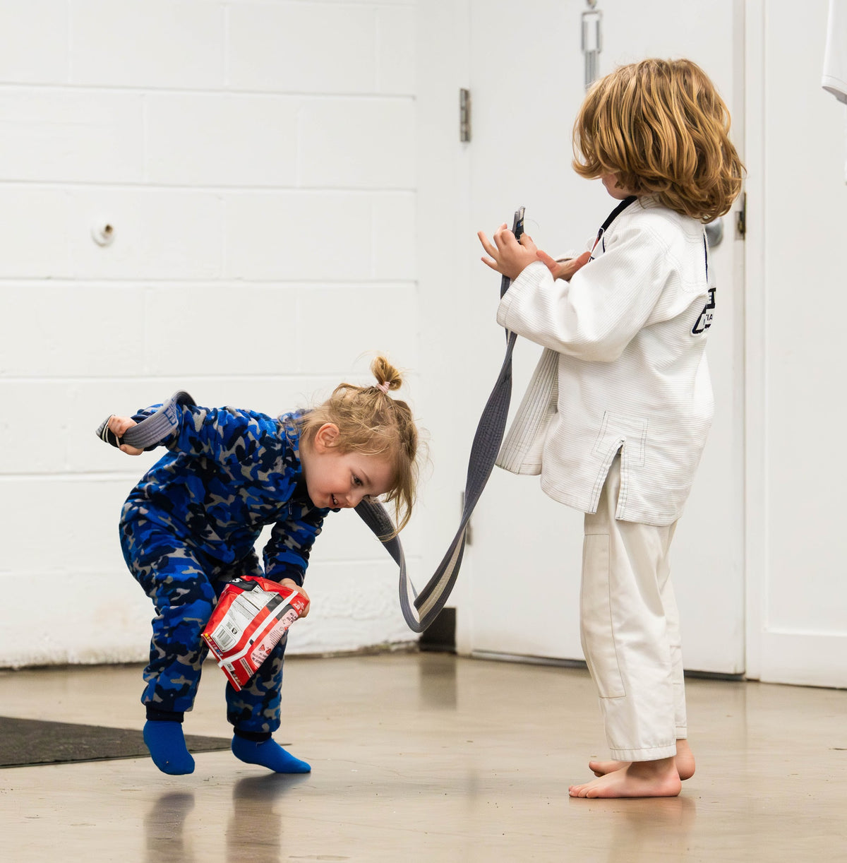 Two young children playing a belt game in Tumblers and Tots BJJ at One Way Martial Arts in Alexandria, VA